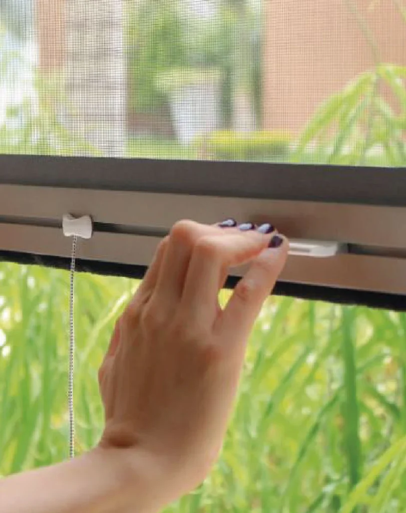 mujer cerrando ventana con persiana mosquiteros